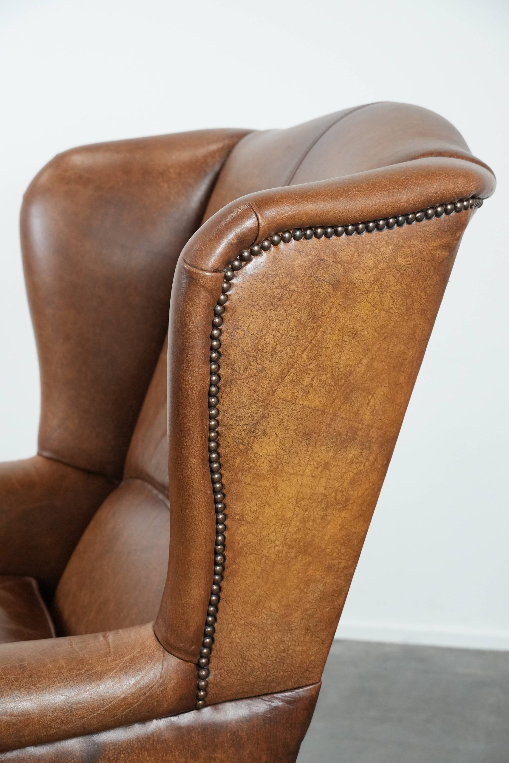 Cognac-coloured wingback armchair in English style made of cowhide leather