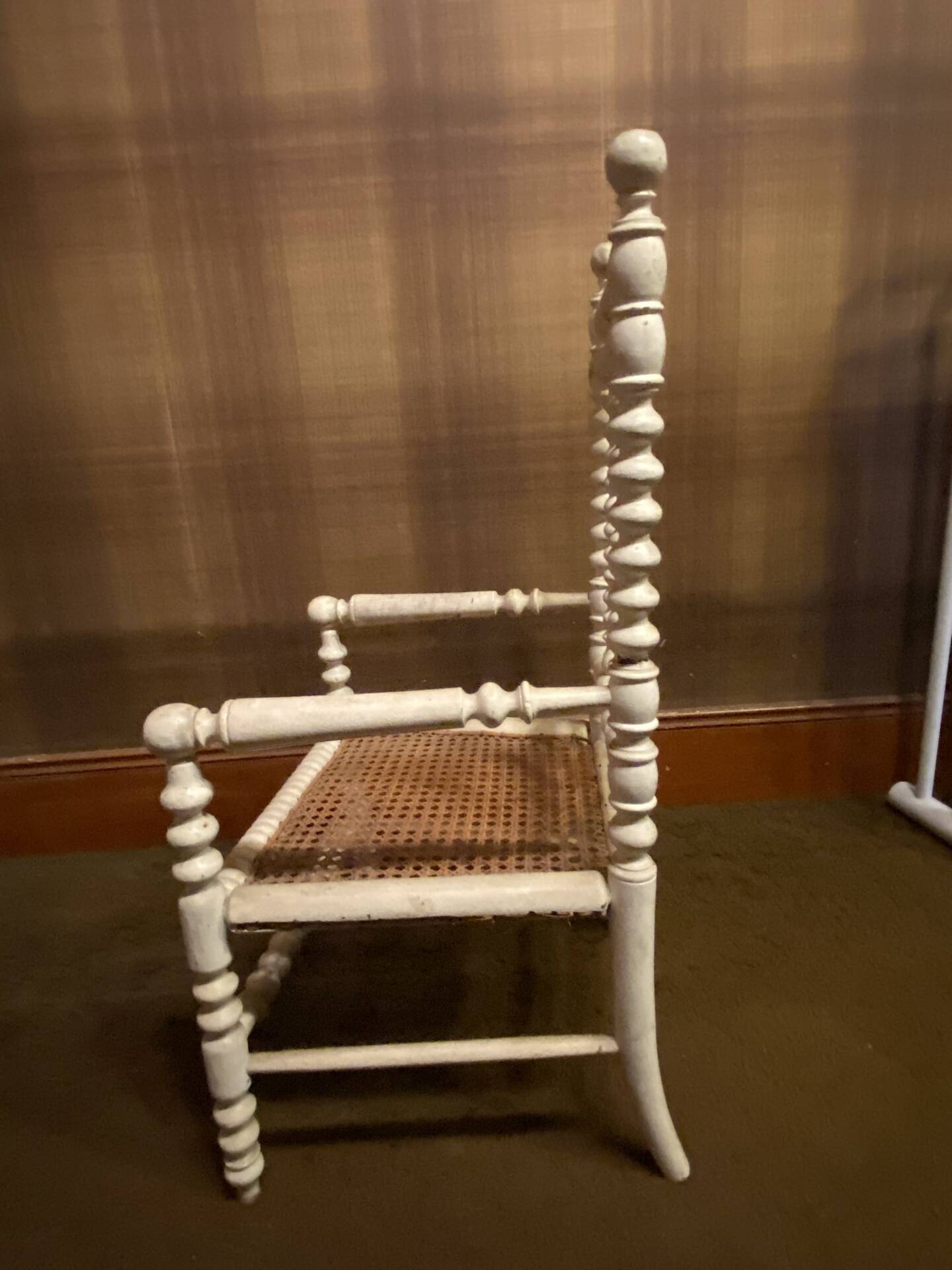Antique wooden child's chair with turned legs and caning, white patina.