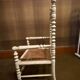 Antique wooden child's chair with turned legs and caning, white patina.