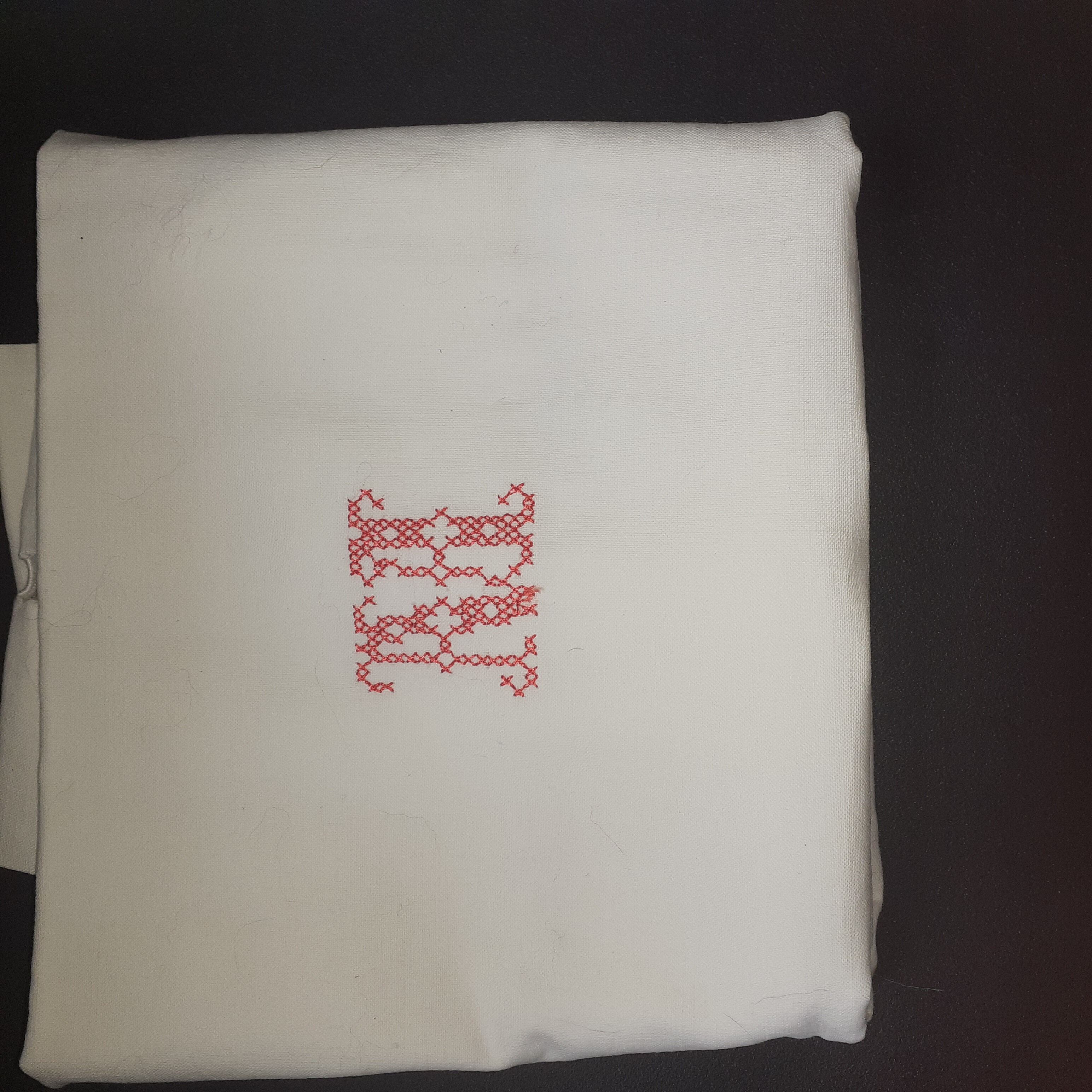 Pillowcase, red central monogram. Surrounded by days.