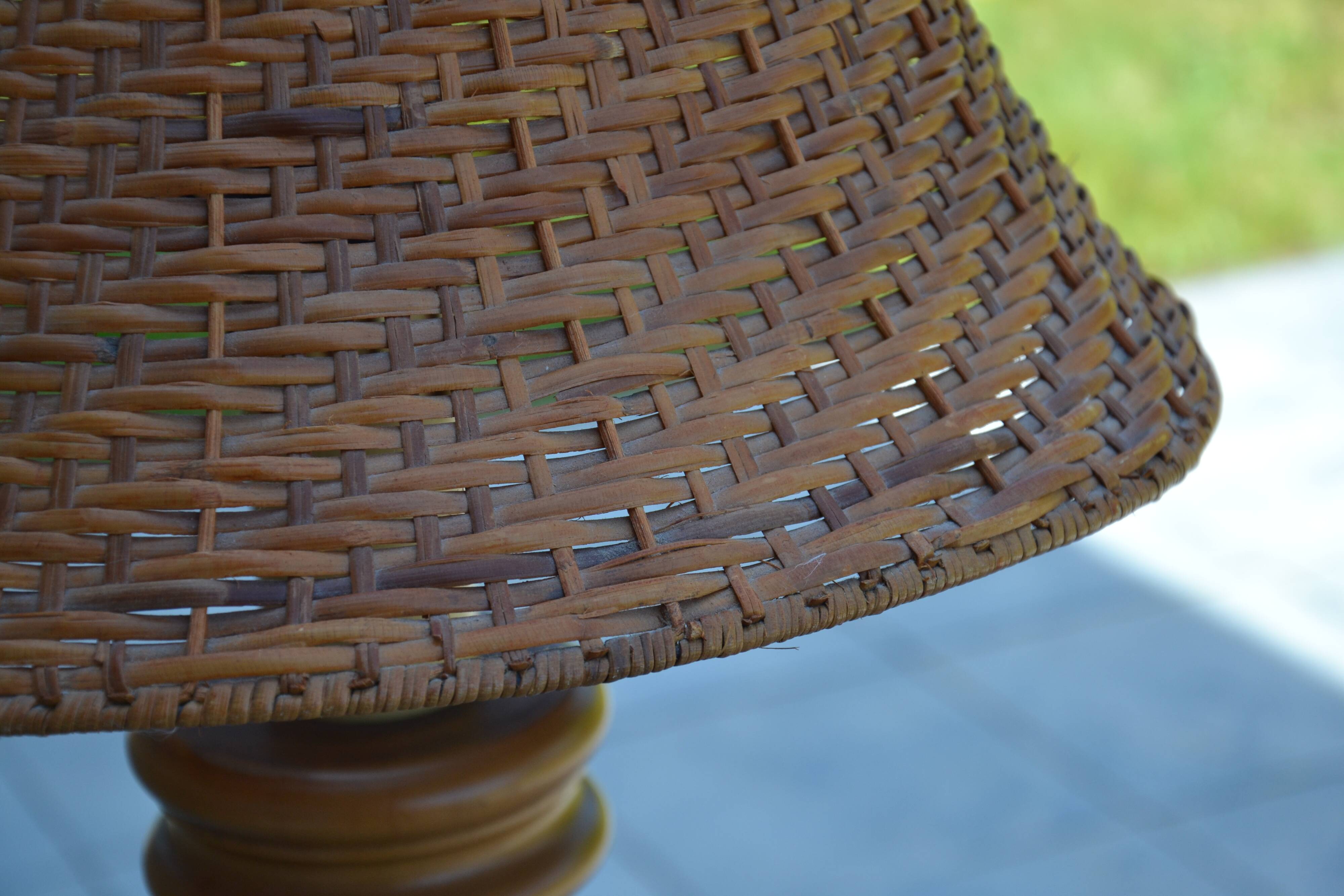 Large wooden lamp with a woven rattan shade.