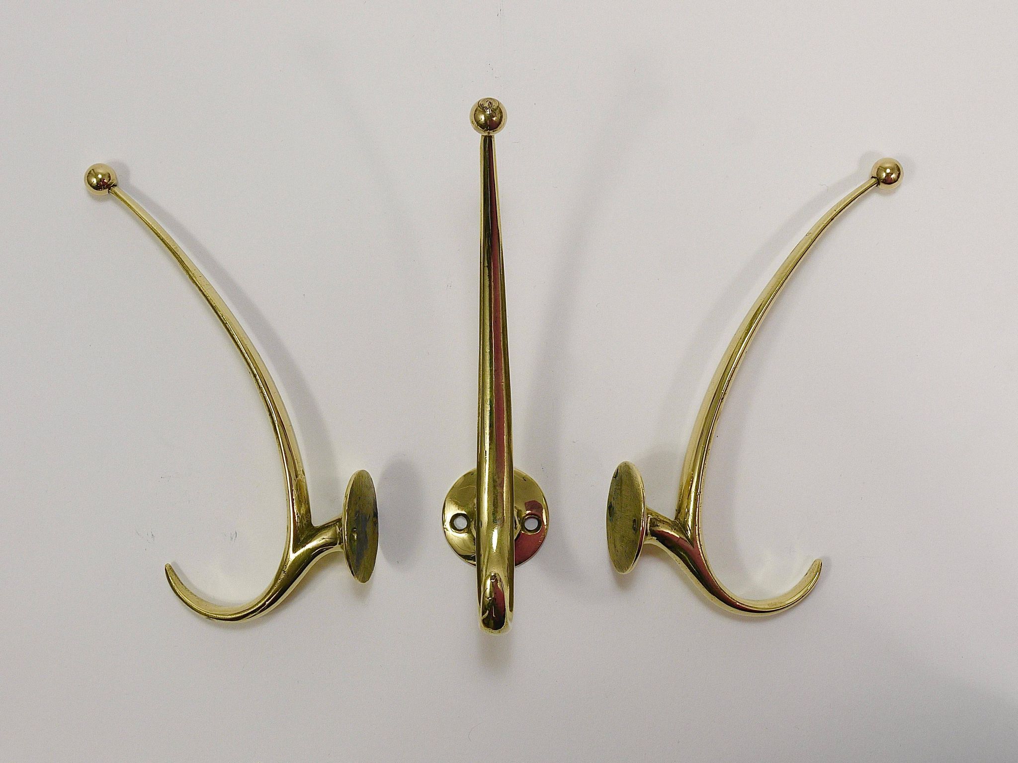 Two curved wall coat racks in brass by Franz Hagenauer, Vienna, mid-20th century, 1950s.