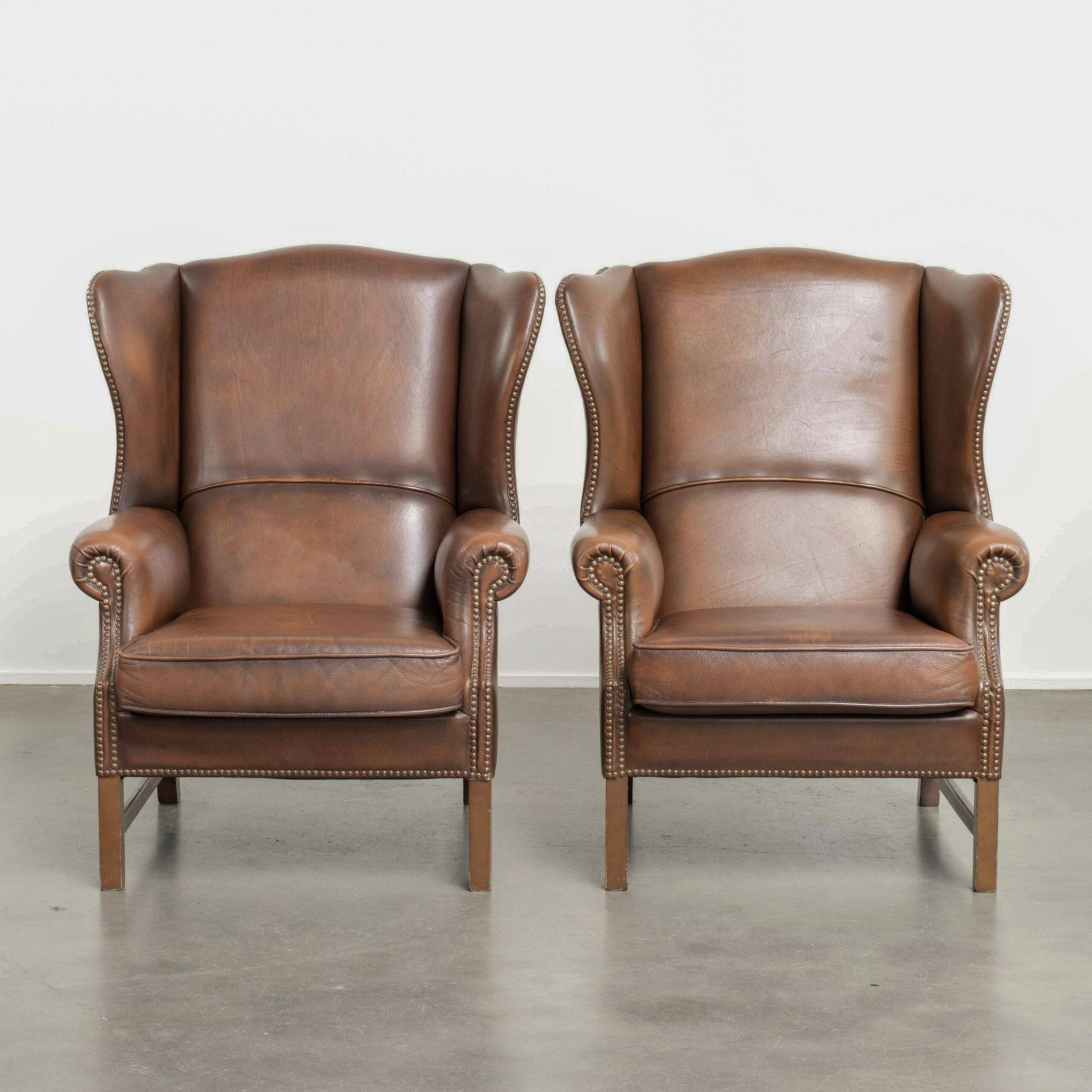 Ensemble de 2 fauteuils à oreilles en cuir de vache de style anglais.