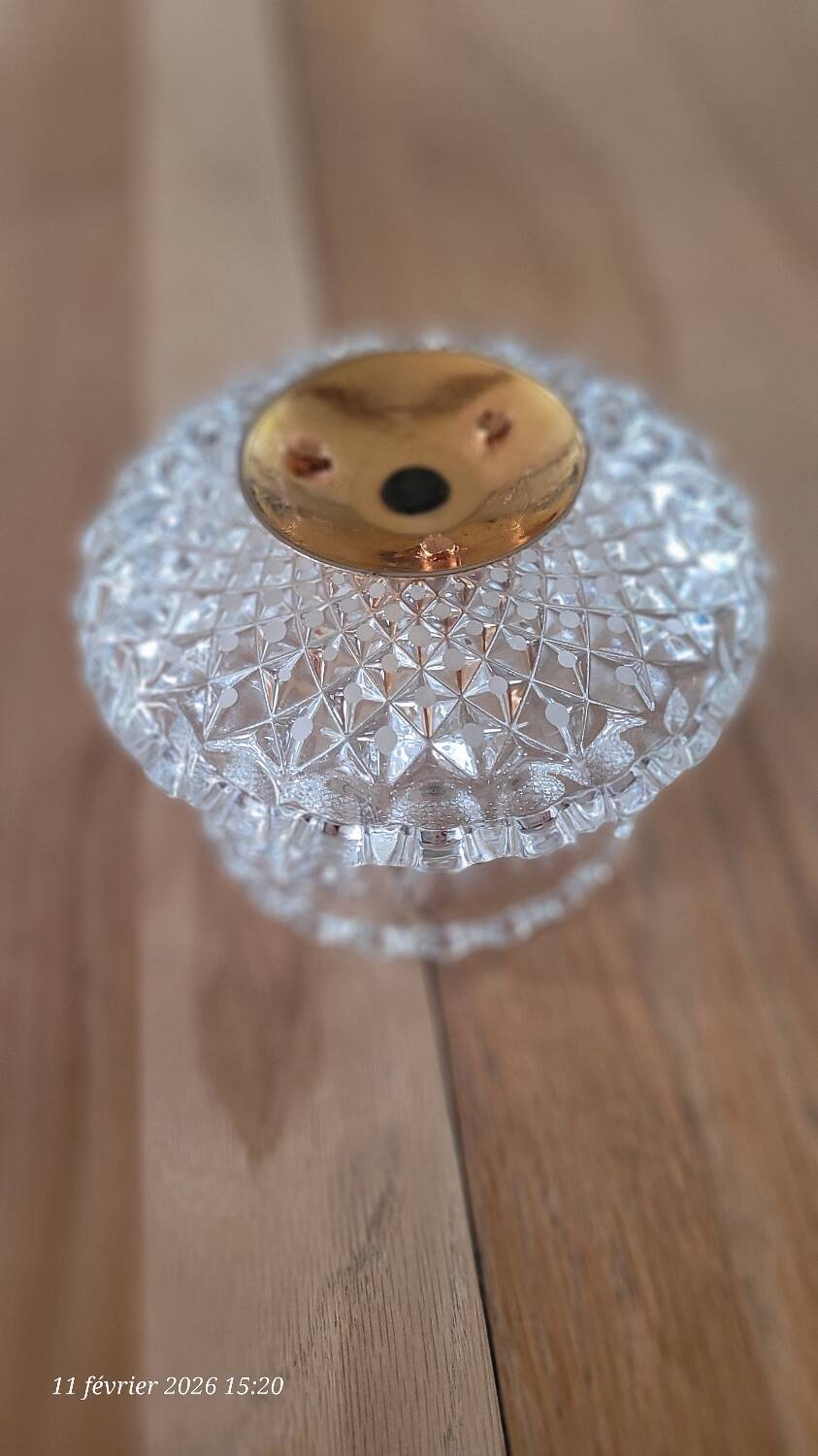 Two-tier display stand in cut glass mounted on a gold metal base.