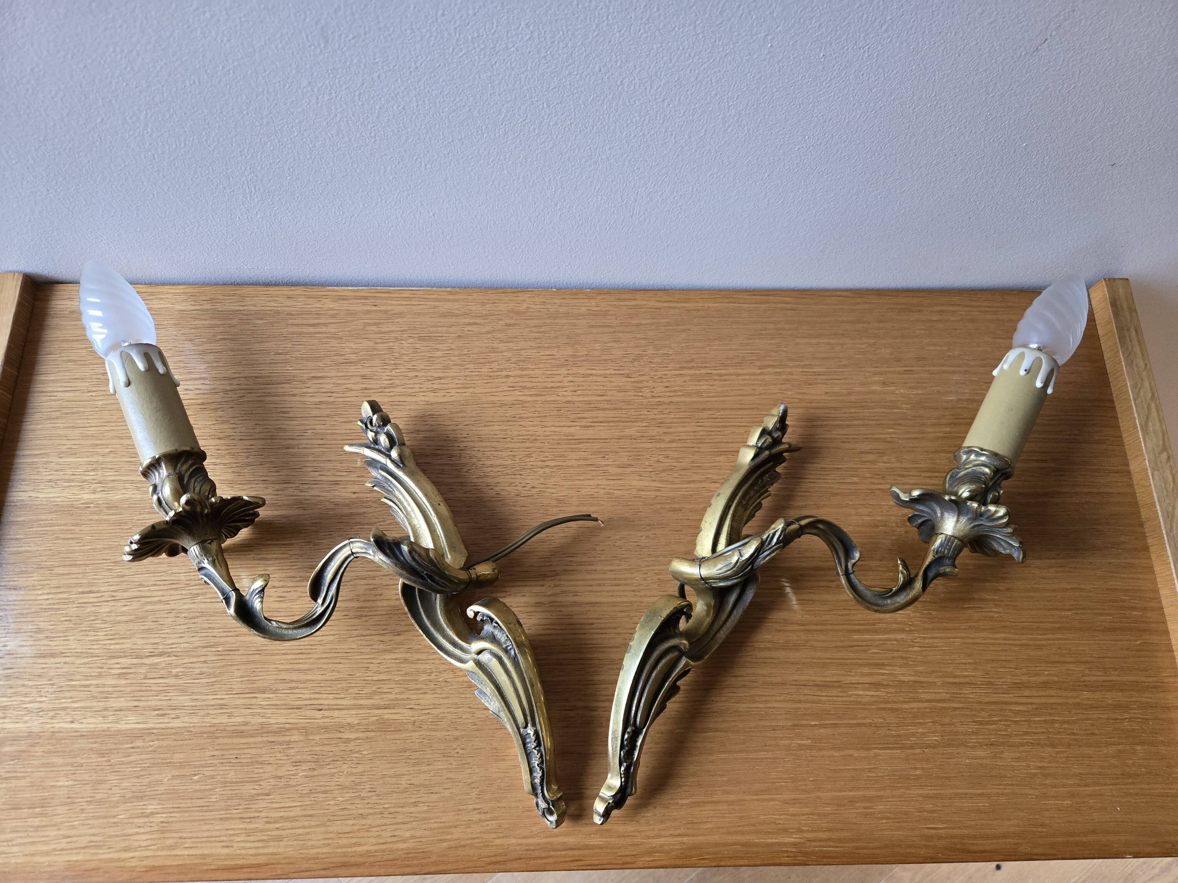 Pair of symmetrical gold wall sconces in baroque style made of bronze.