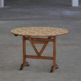 19th-century French round wine table with an adjustable top and floral textile surface.