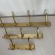 Three vintage 1960s gold coat racks with 4, 3 and 2 hooks