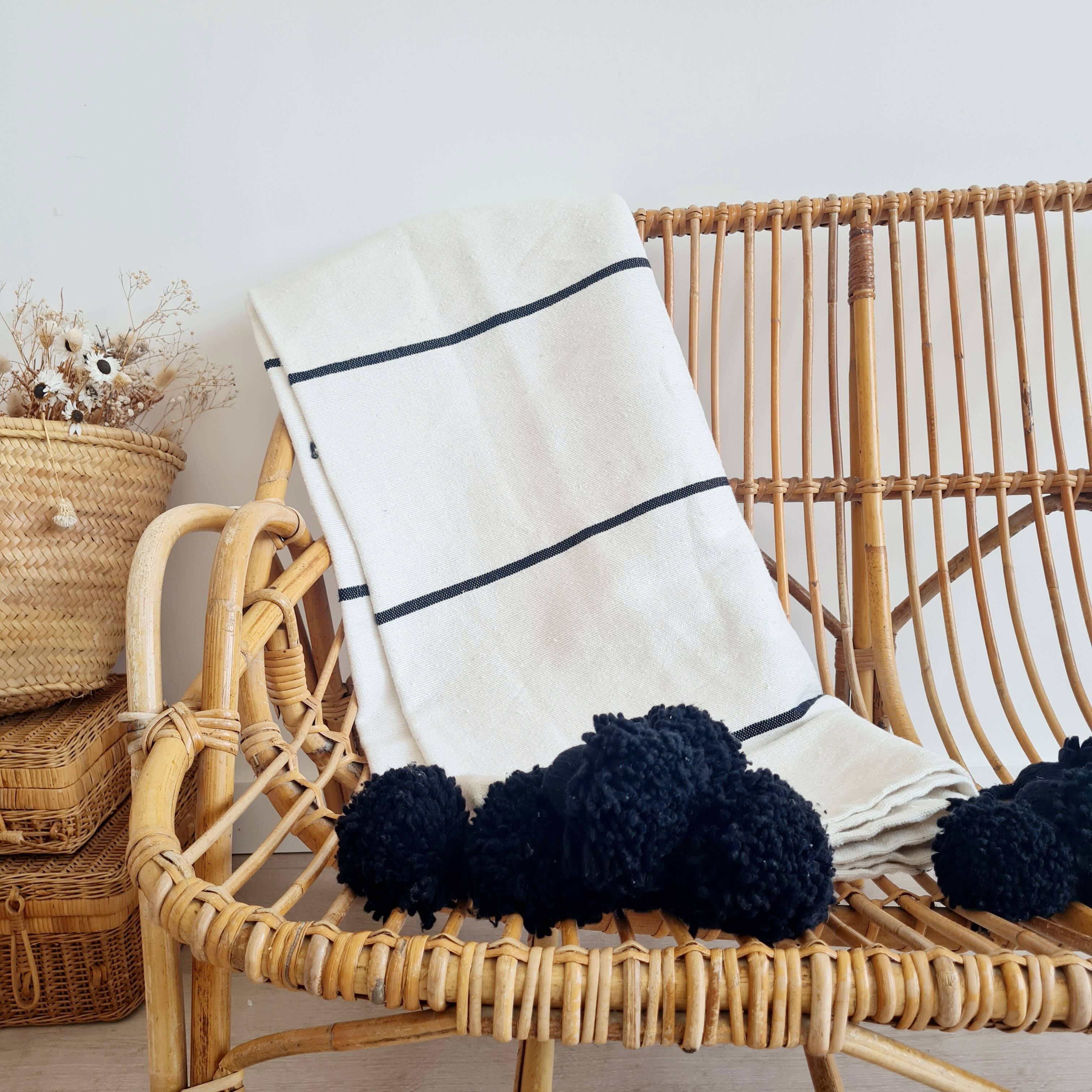 Handwoven throw with black stripes and pom-poms