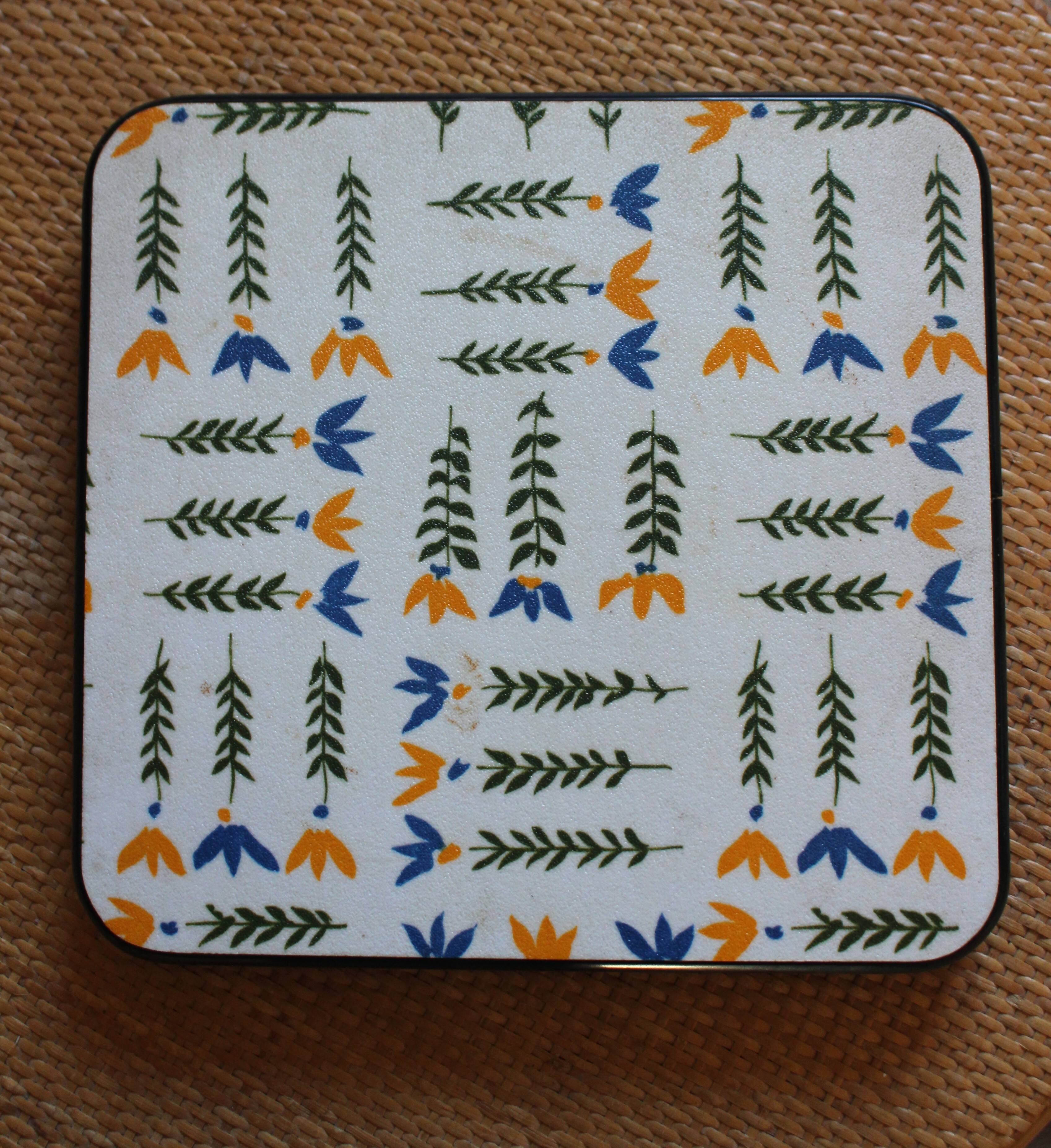 Vintage laminated wooden trivet with yellow, green, and blue flowers