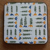Vintage laminated wooden trivet with yellow, green, and blue flowers
