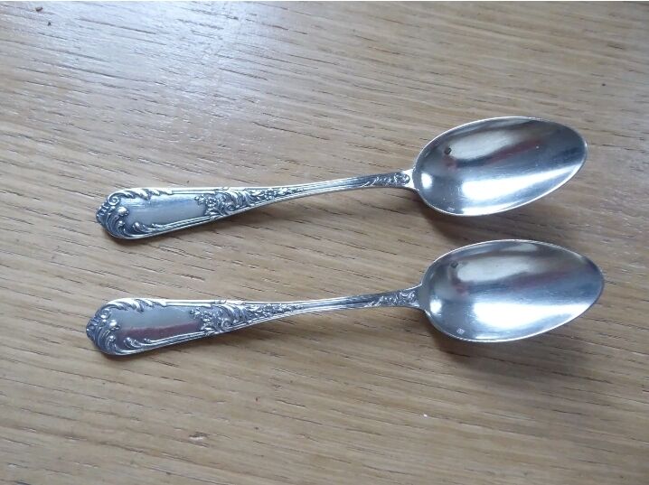2 small white metal spoons