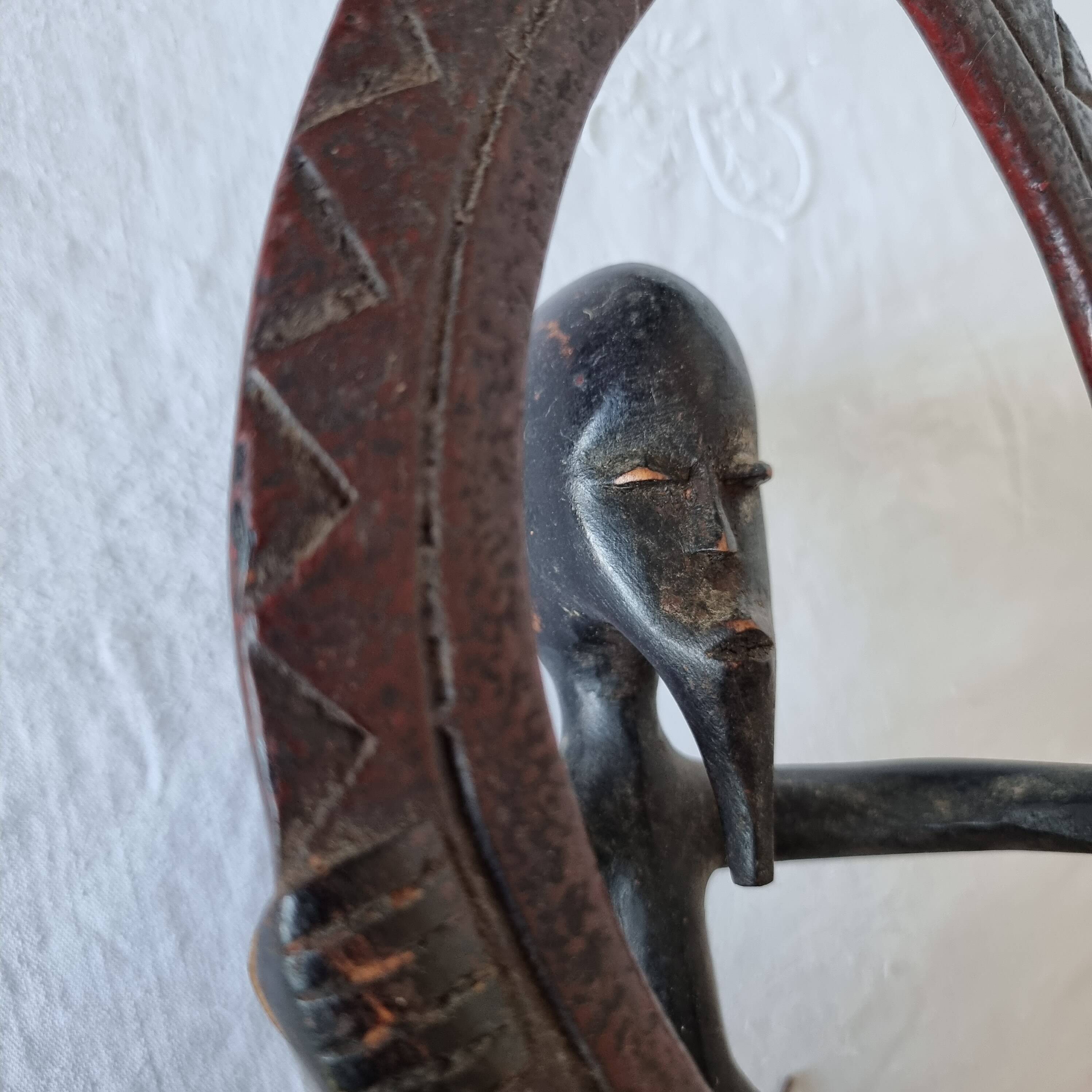 A large Senufo mask made of colored wood, decorated with an anthropomorphic figure