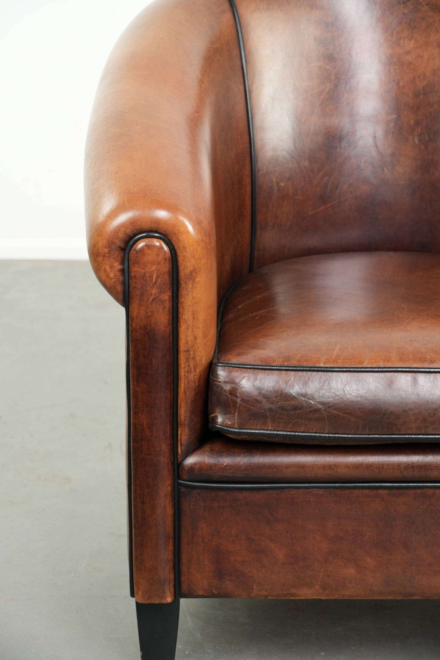 Sheepskin club armchair with deep warm colours and black piping