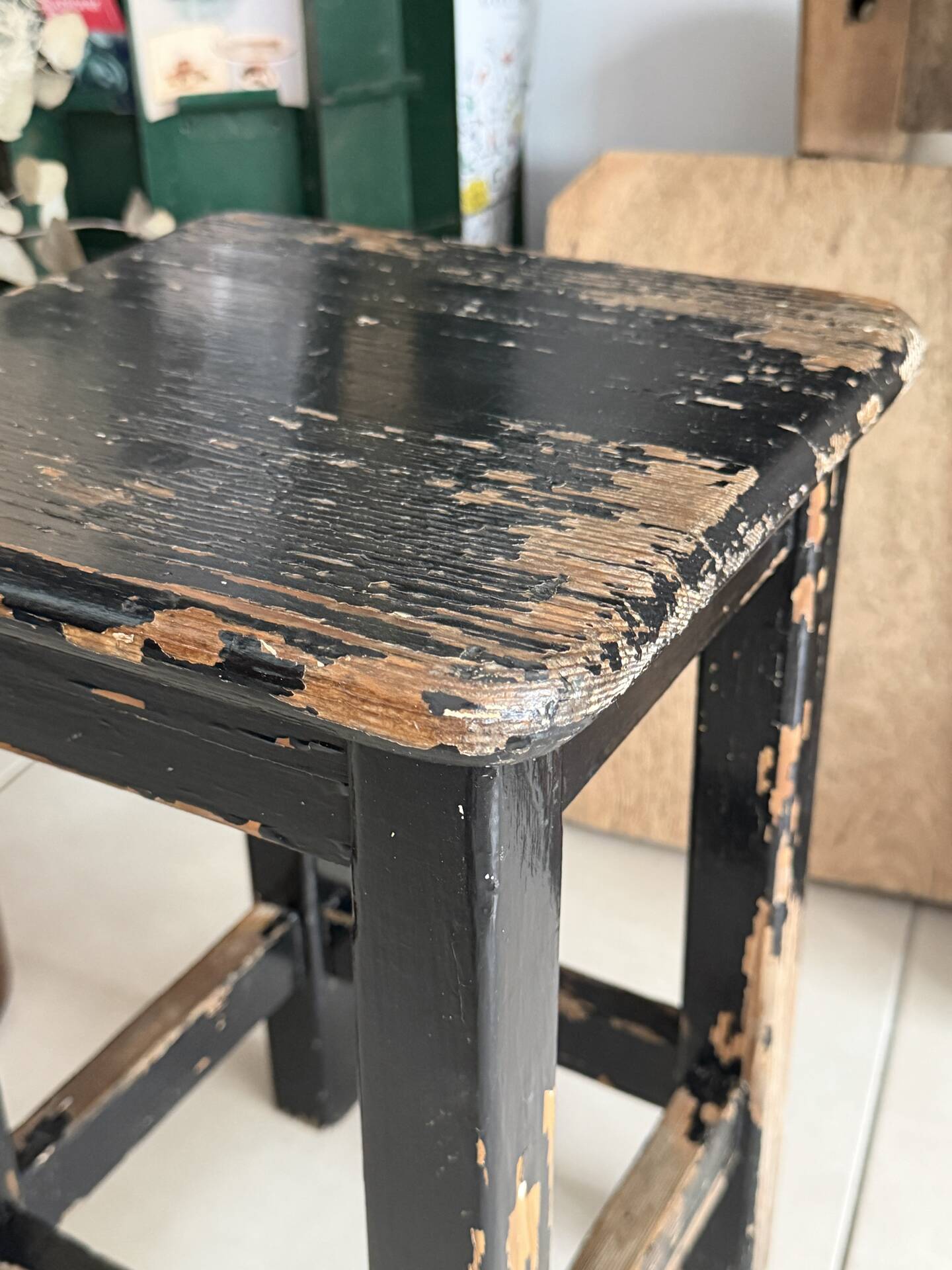 Solid wood stool with a worn black patina.