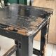 Solid wood stool with a worn black patina.