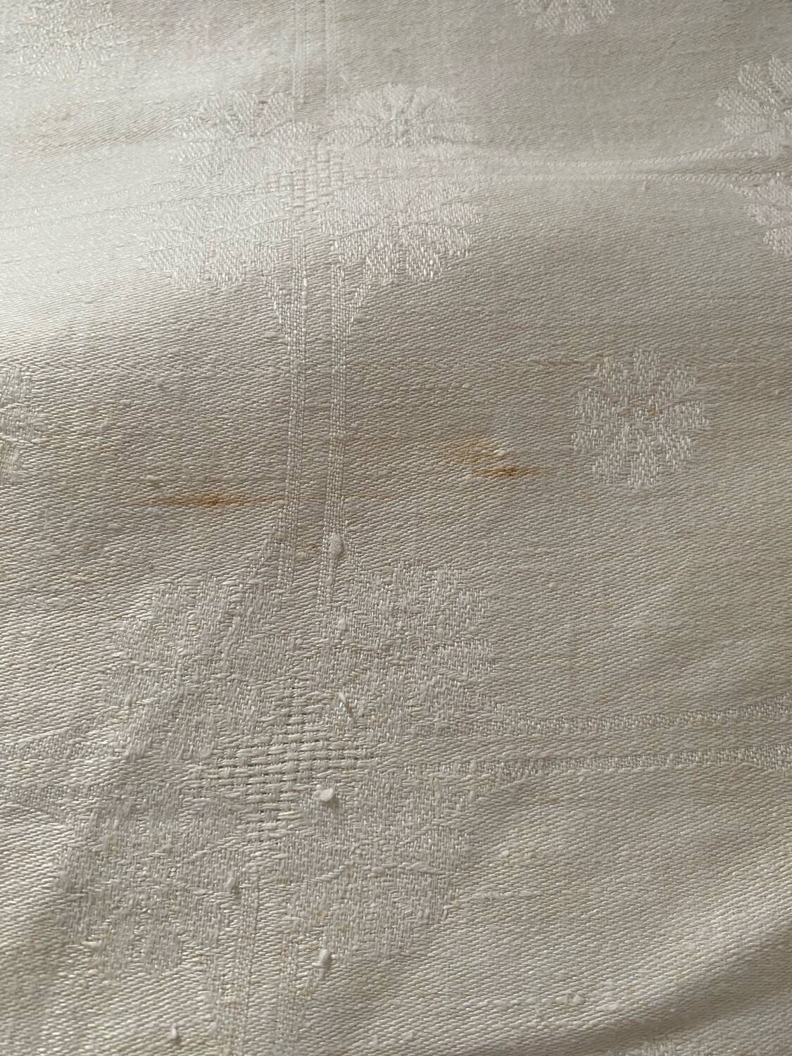 Damask tablecloth with a floral pattern and a central embroidered monogram.