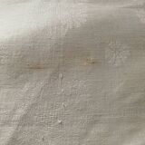 Damask tablecloth with a floral pattern and a central embroidered monogram.