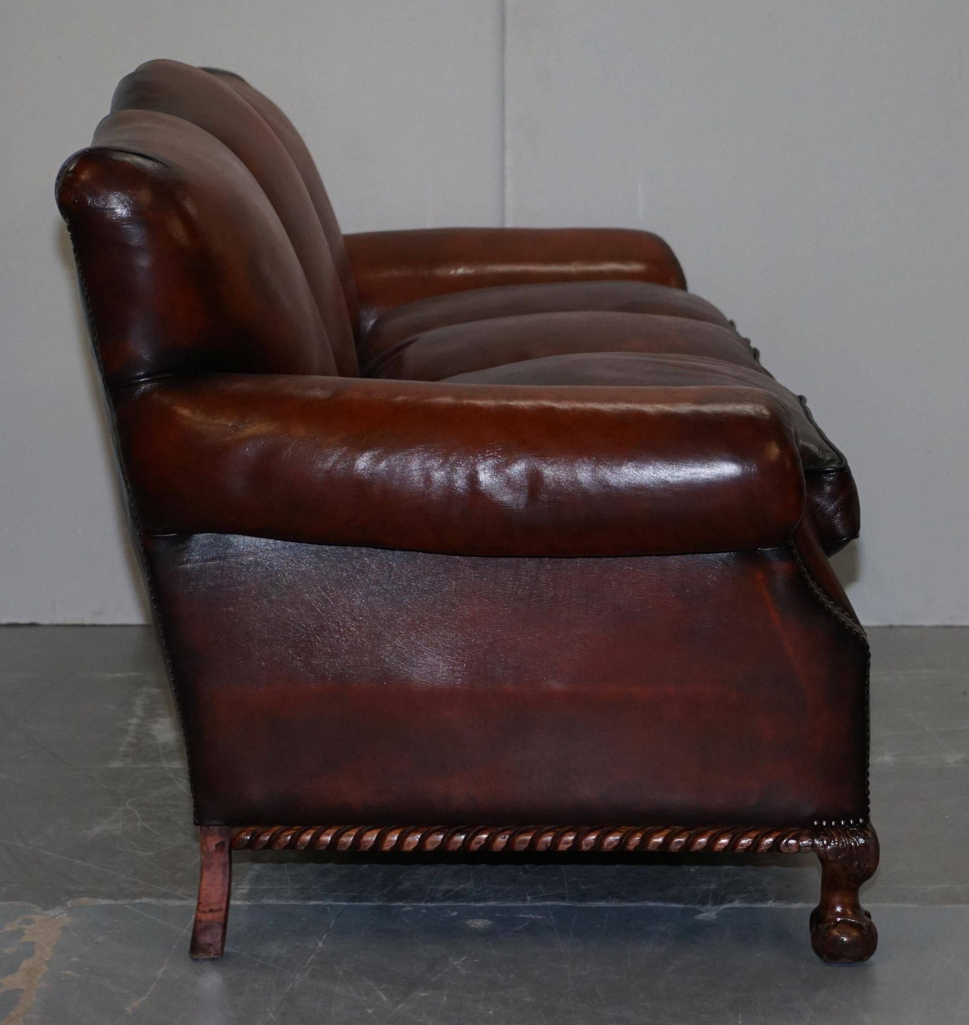 Restored Victorian sofa in leather with claw feet and feather cushions.