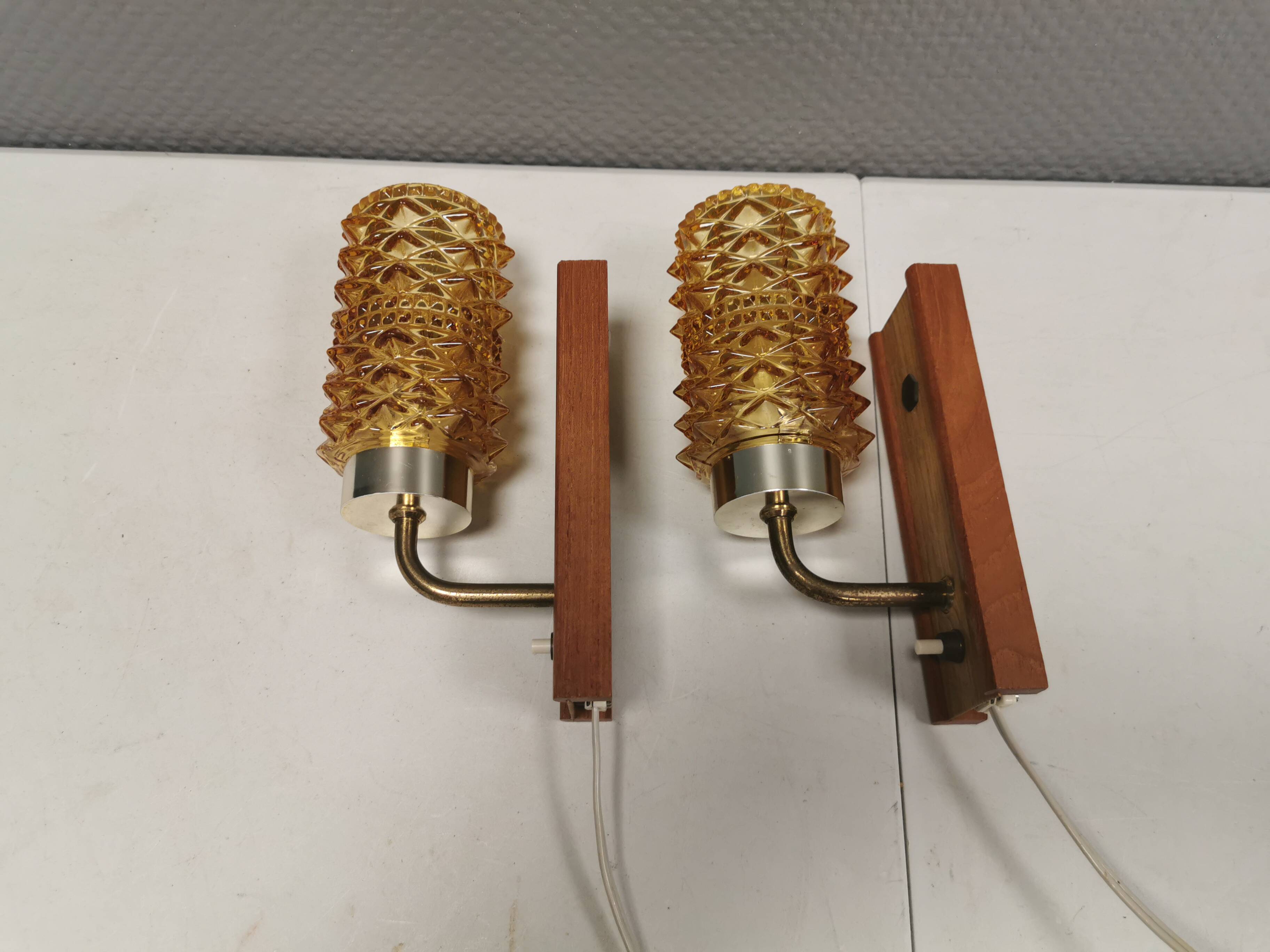 A set of wall lamps in teak wood, with amber colored glass