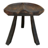 Tripod stool made of solid wood, with a carved seat.