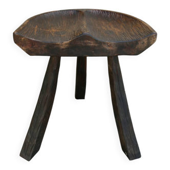 Tripod stool made of solid wood, with a carved seat.