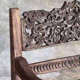 Small antique Indonesian bench in carved teak with plant and floral motifs.
