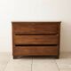 Antique solid wood chest of drawers with a white marble top.
