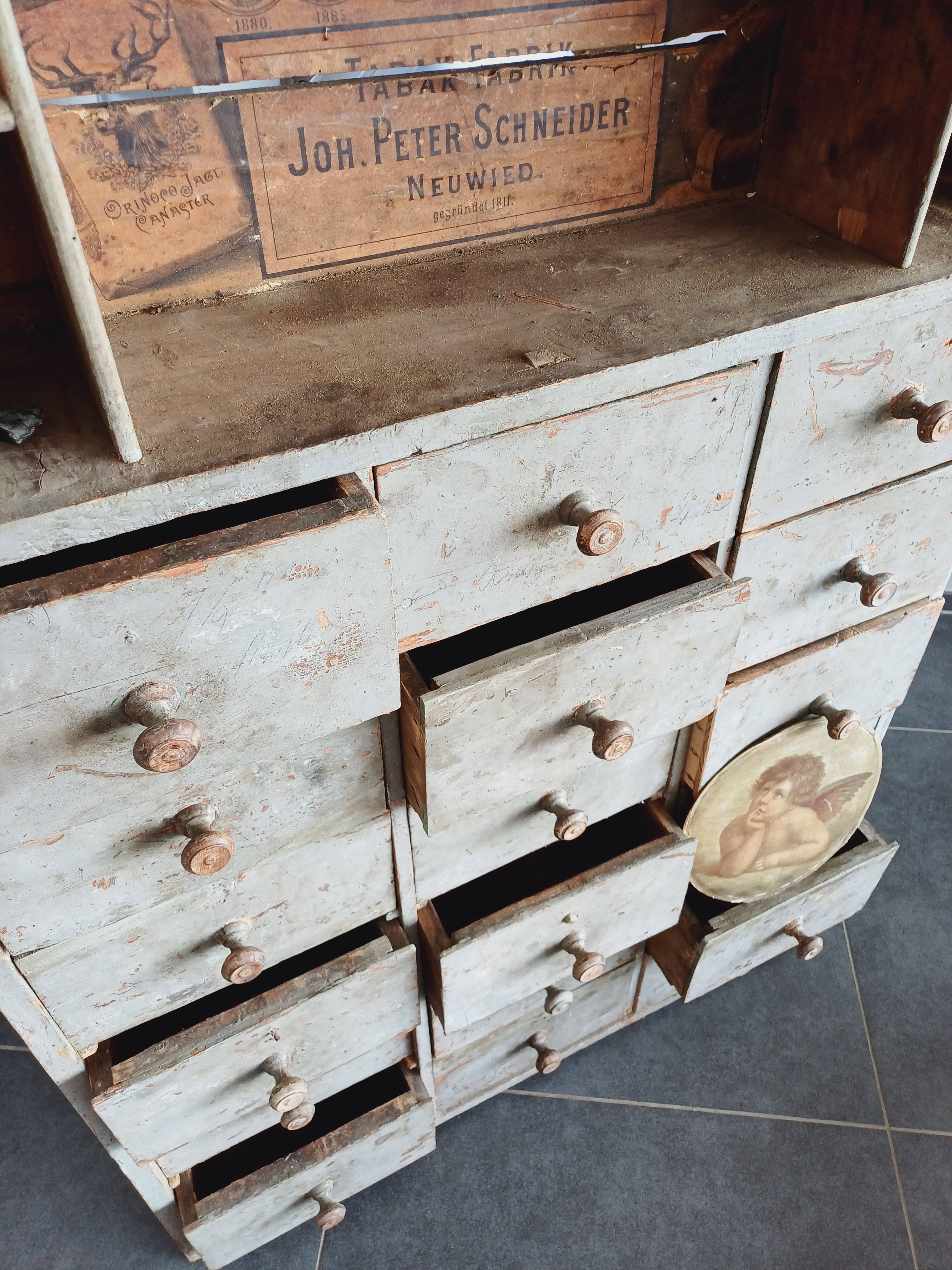 Craft cabinet with drawers with a very old tobacco advertisement in the background