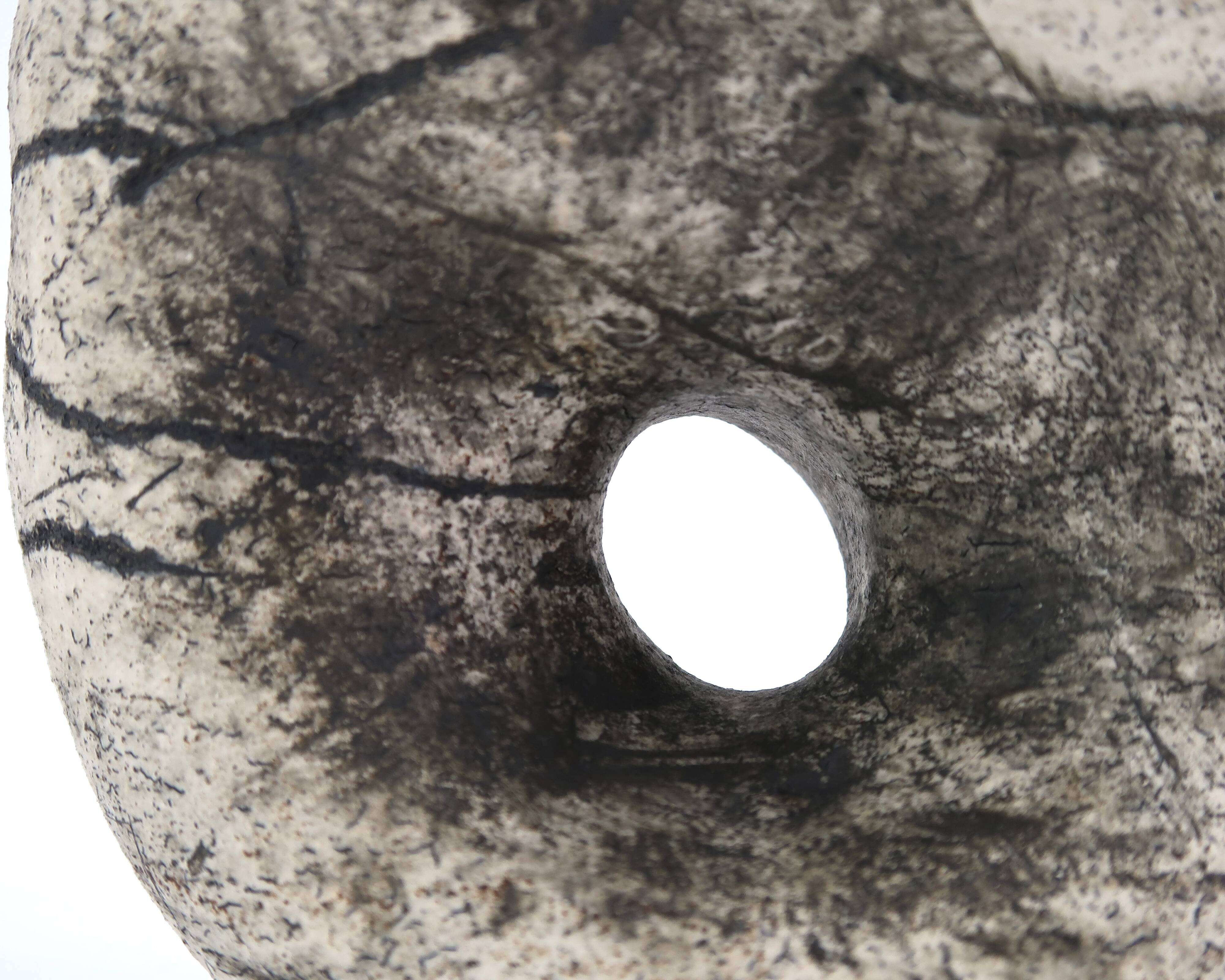 Ceramic vase sculpture decorated with faces and featuring a hole, 1980s.