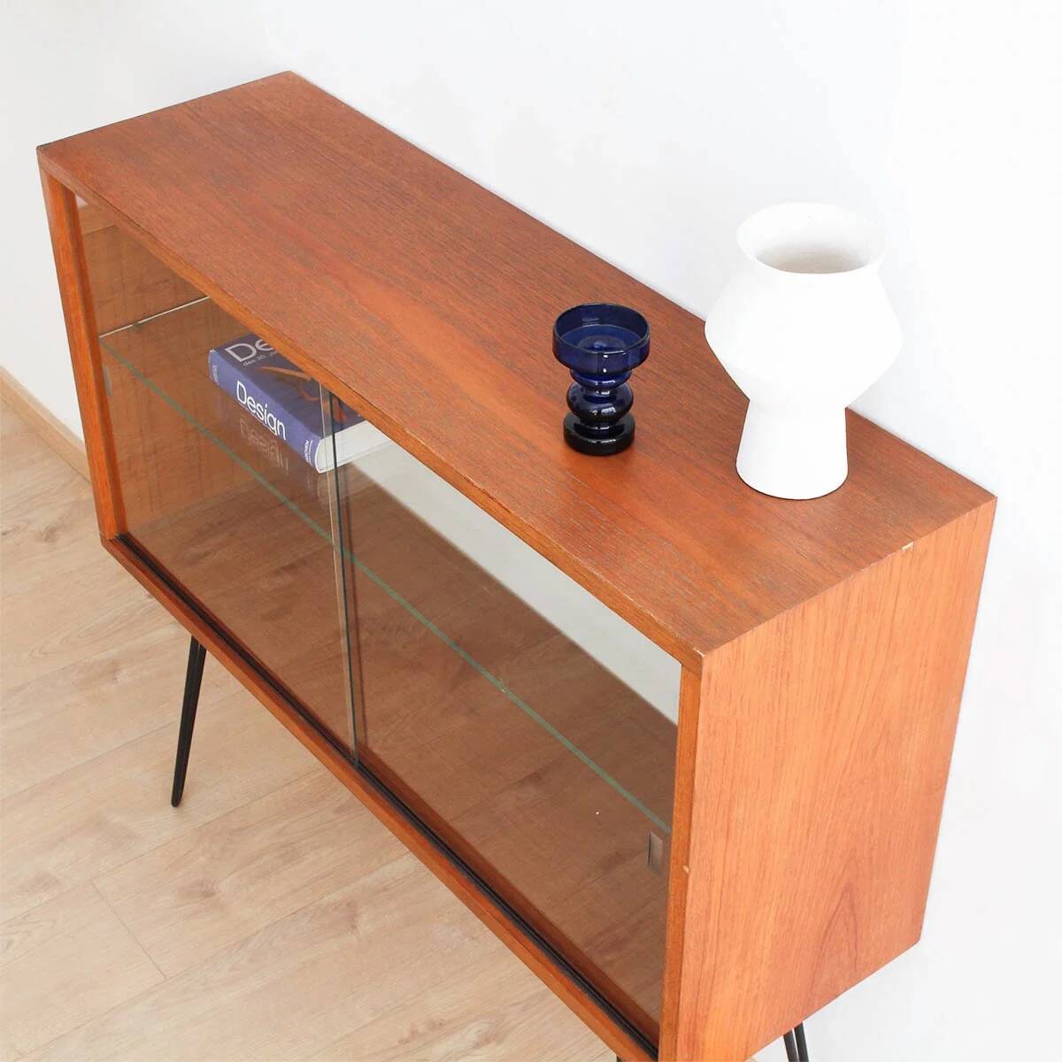 Teak display cabinet with black hairpin legs.