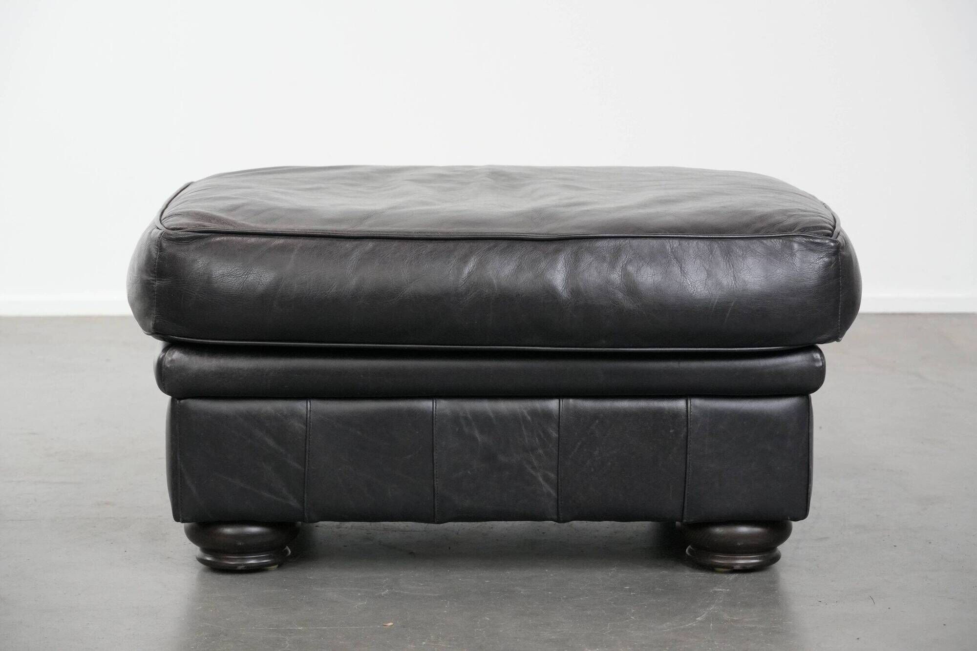 Set of a black cowhide leather Chesterfield armchair and matching ottoman