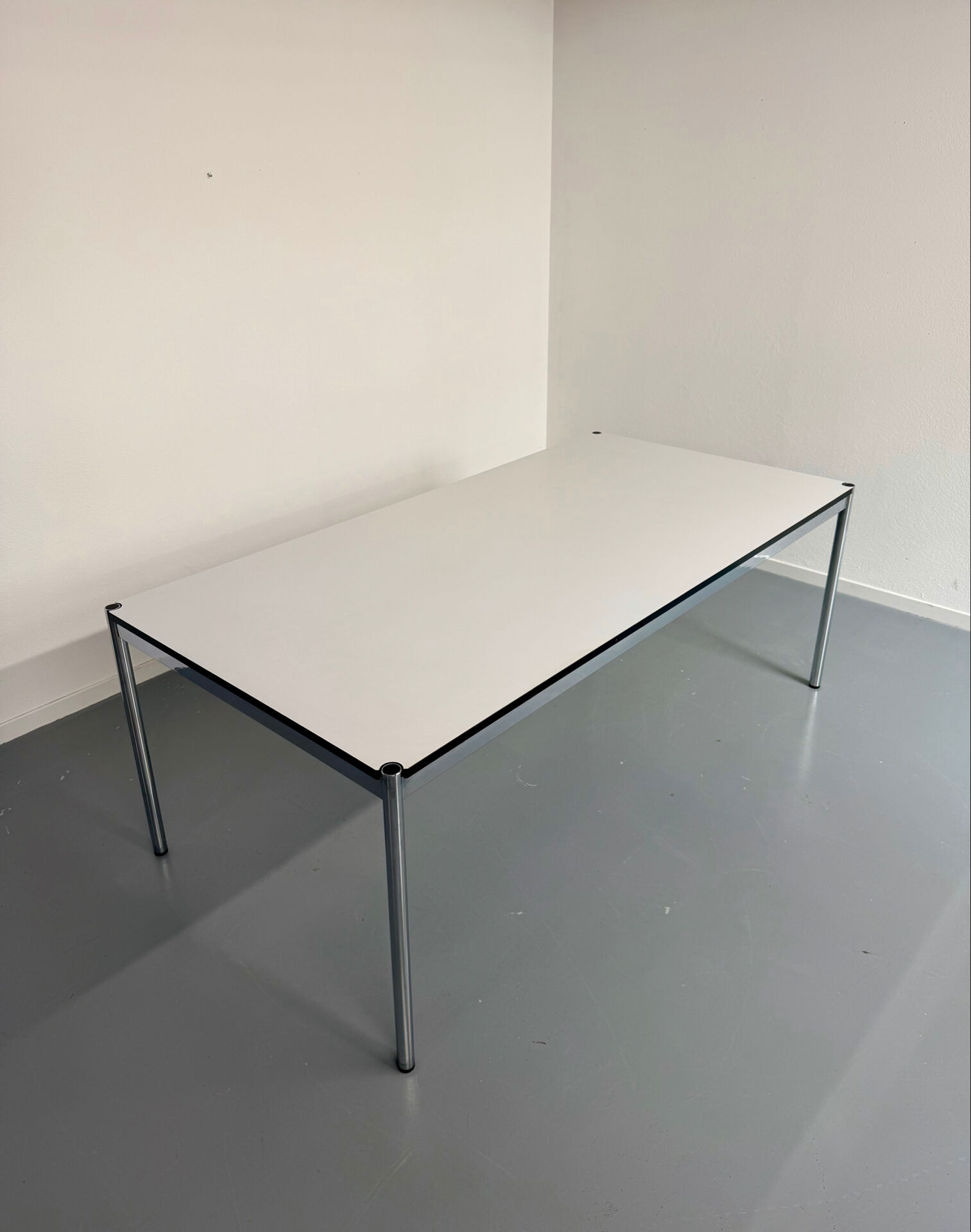 Large table design USM Haller with a white top and chrome structure.