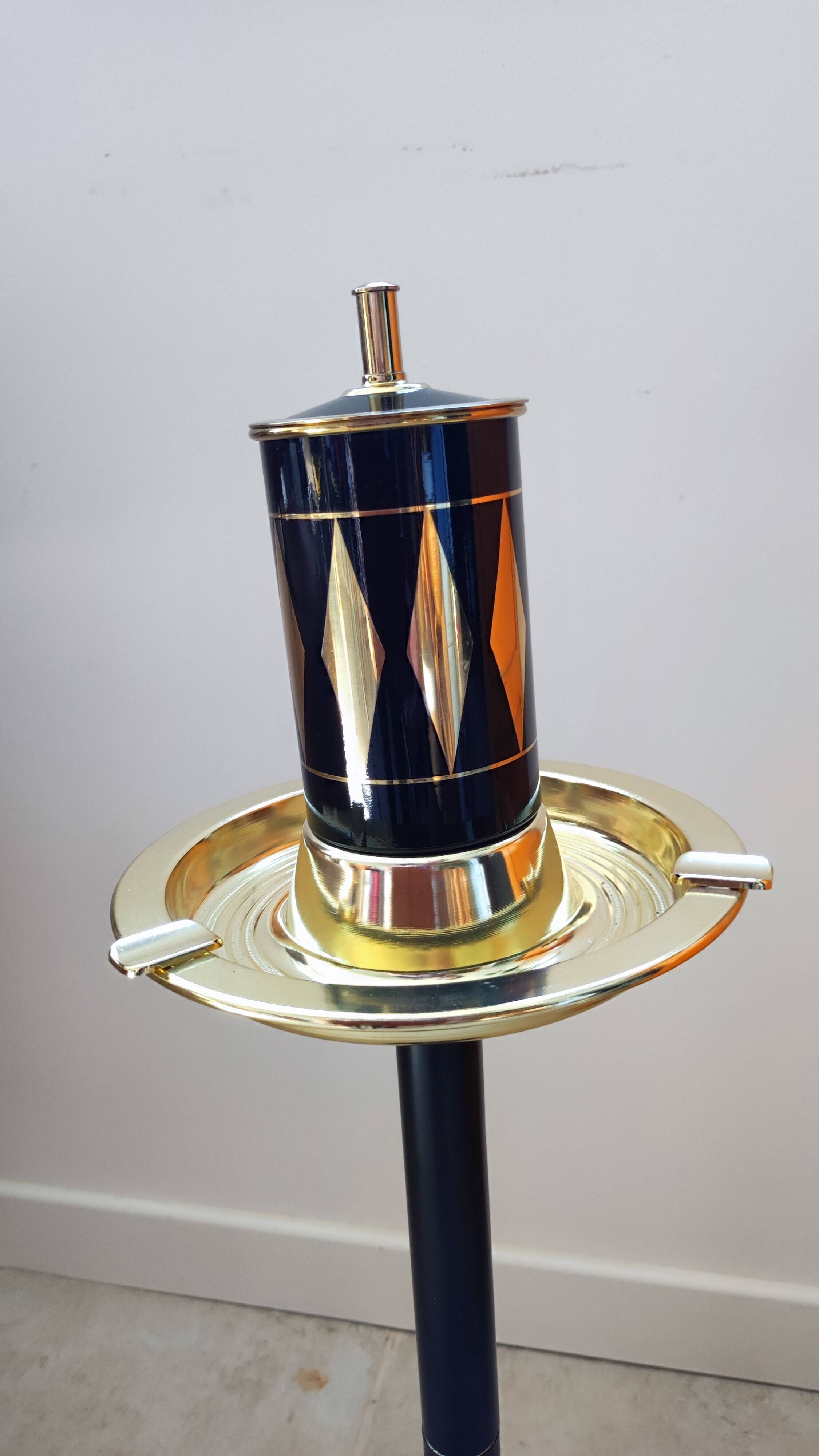 Vintage floor ashtray with a gold and black metal cigarette dispenser.