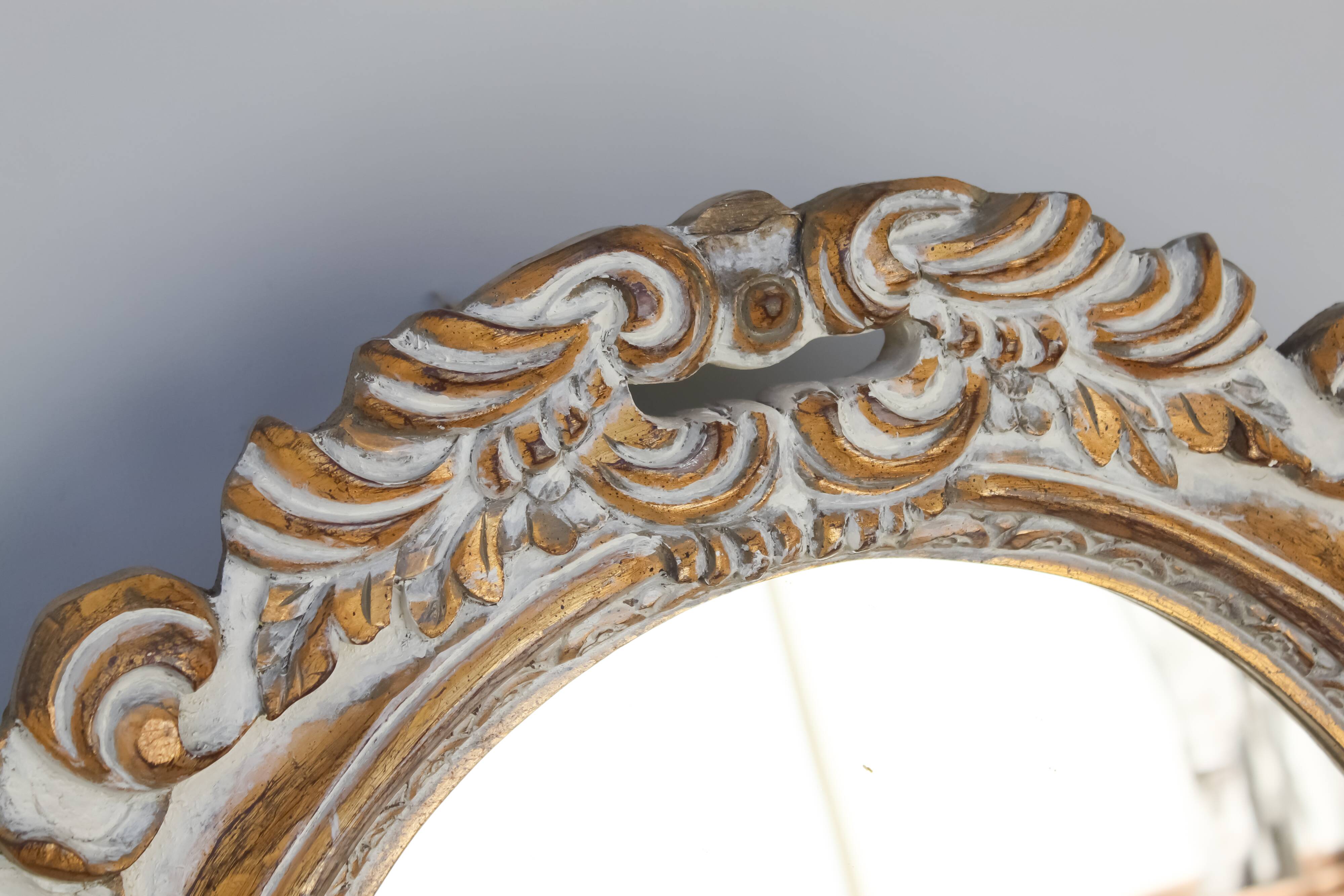 Distressed and carved golden oval mirror in wood.