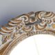 Distressed and carved golden oval mirror in wood.