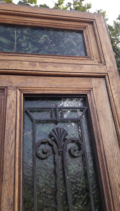 Oak entrance door and its frame and transom, wrought iron gates