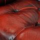 Classic cowhide chesterfield buttonseat armchair in a beautiful red colour and elegant round shapes