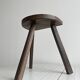 Antique wooden tripod stool with a semi-circular seat.