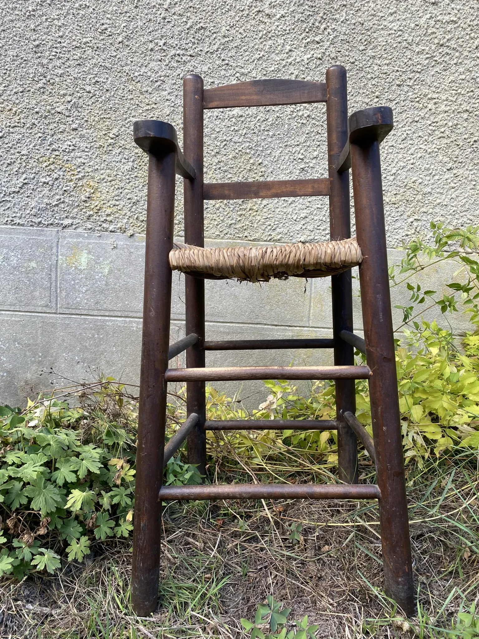 Vintage wooden children's high chair with straw.