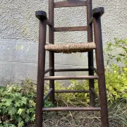 Vintage wooden children's high chair with straw.