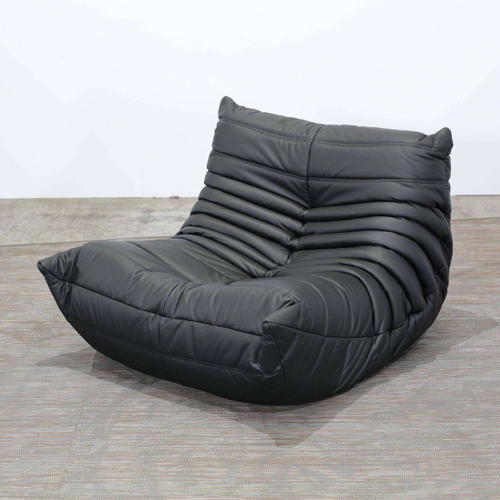 Togo armchair and footrest in black leather by Ligne Roset, designed by Michel Ducaroy.