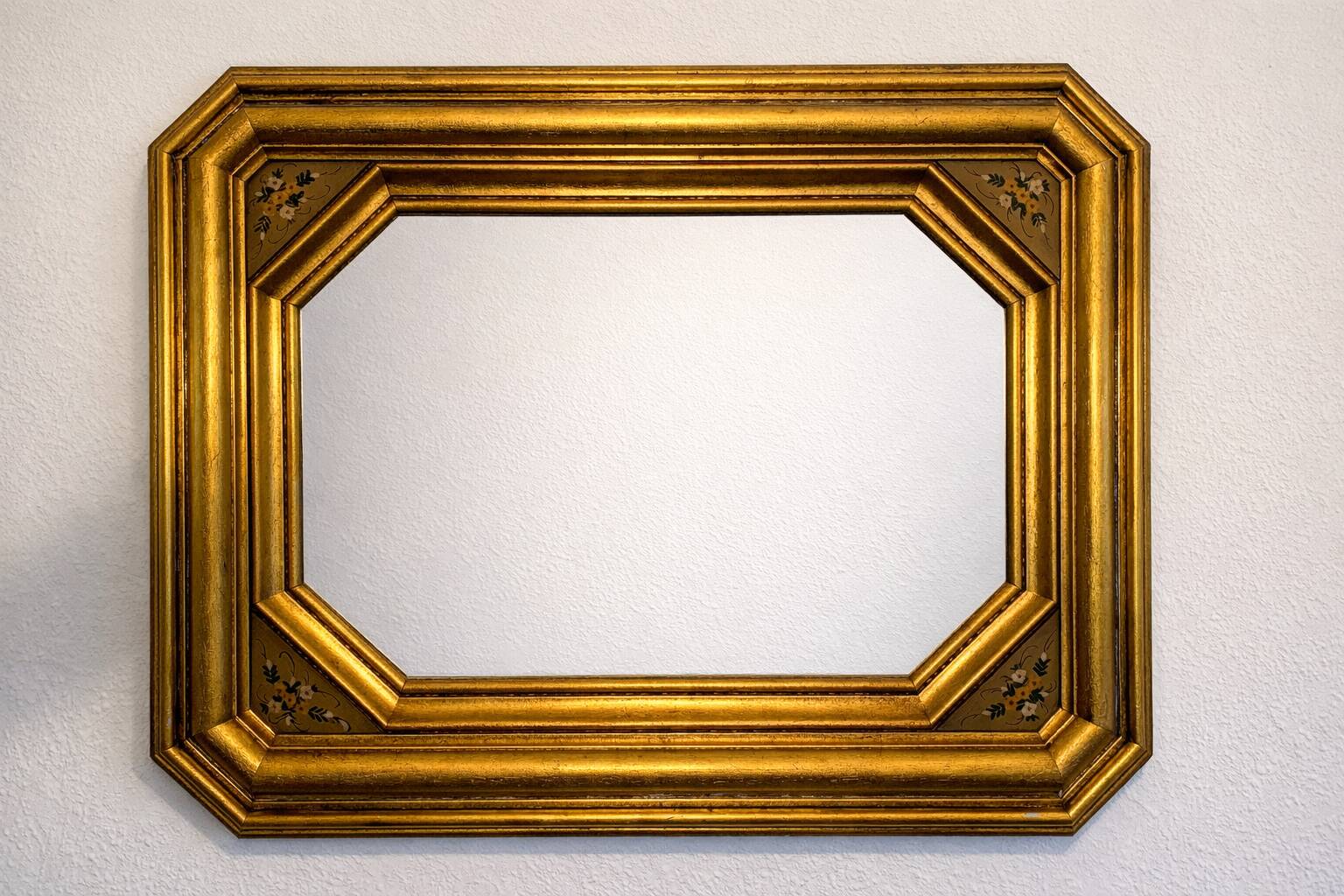 Antique octagonal mirror in gilded wood with painted floral decoration.