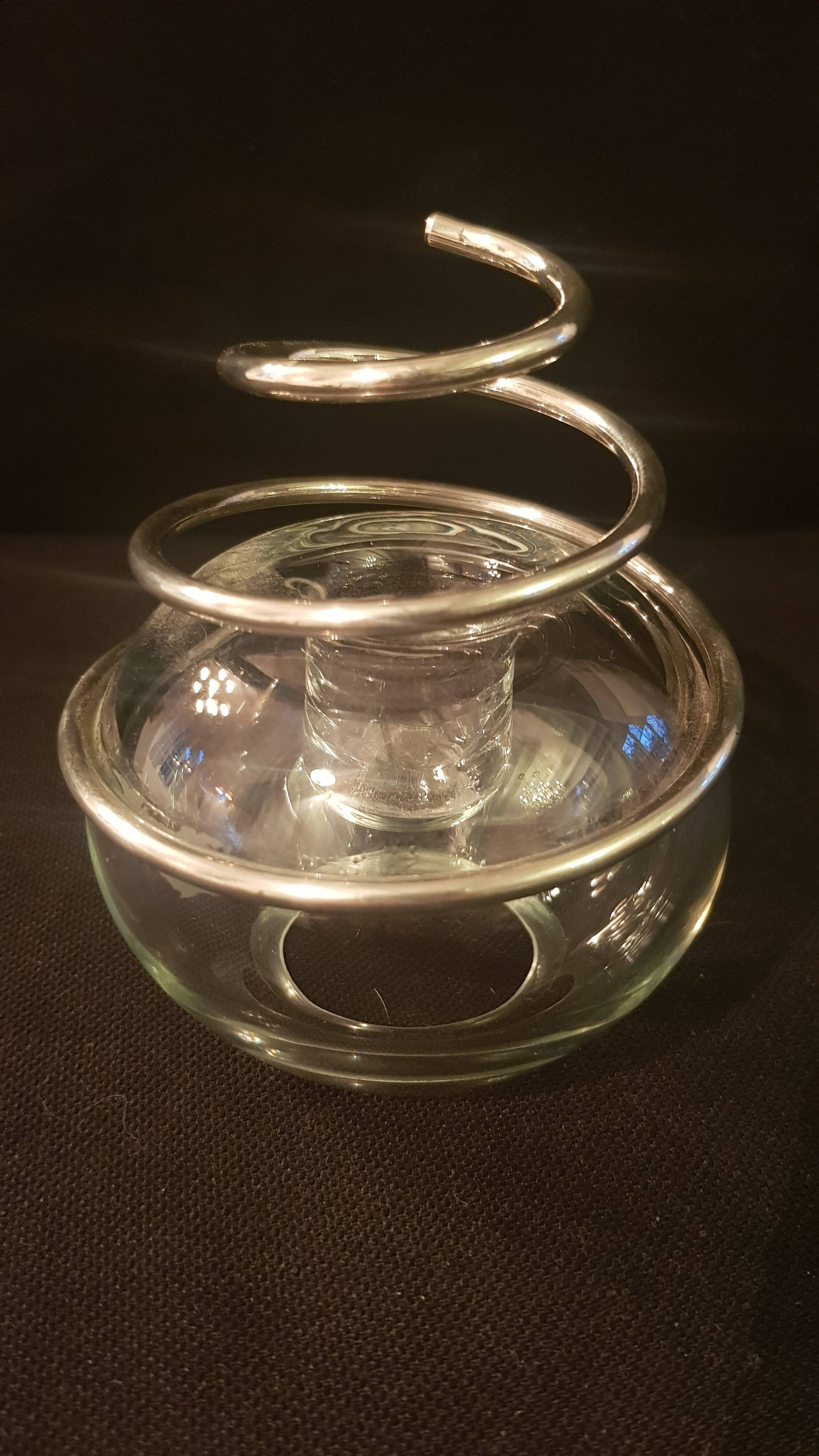 Round glass candle holder with silver-plated metal spiral.