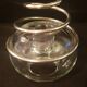 Round glass candle holder with silver-plated metal spiral.
