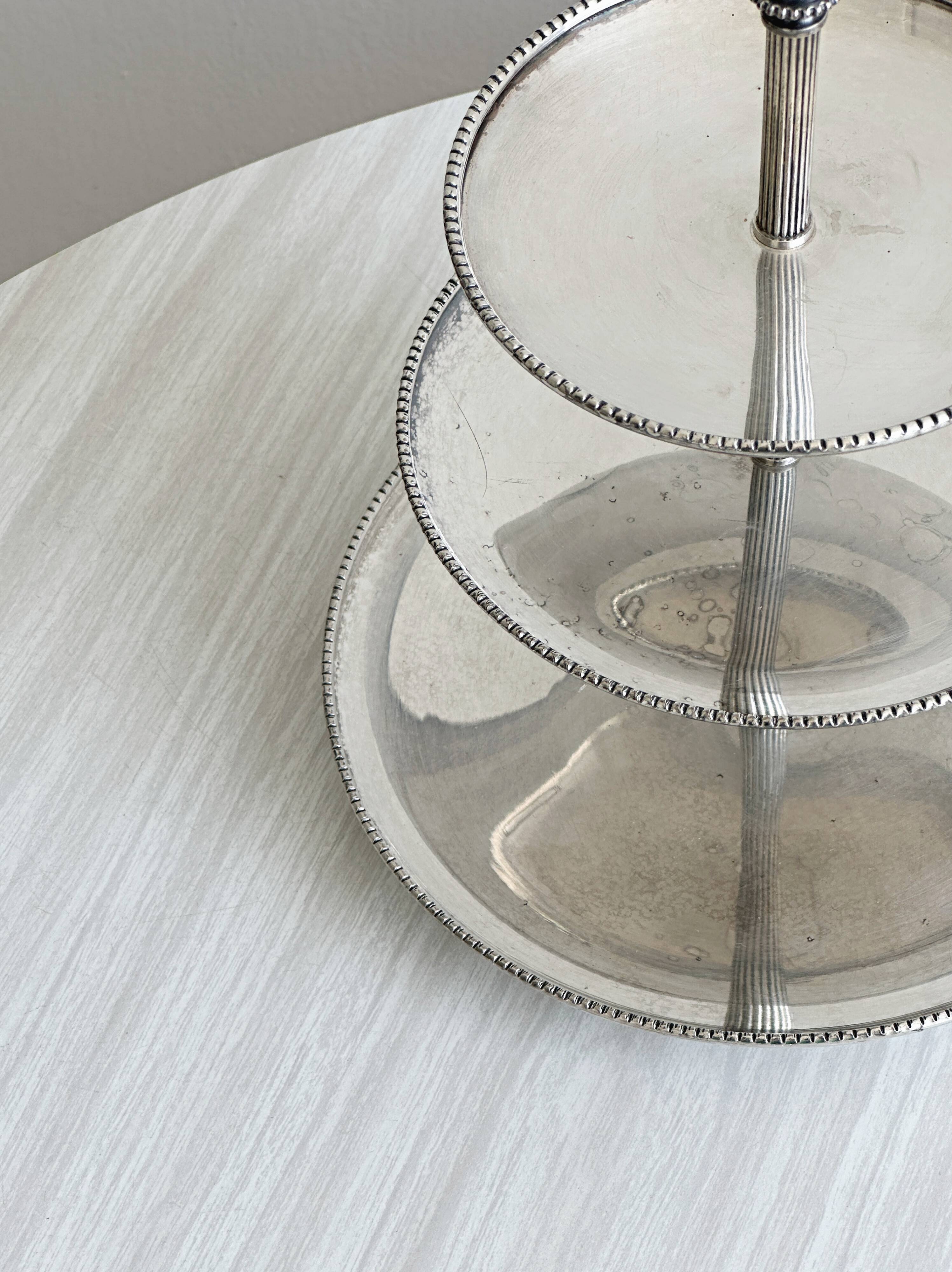 Vintage three-tiered serving stand in patinated silver metal.