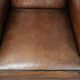 Sheepskin wingback armchair with decorative nails and black piping