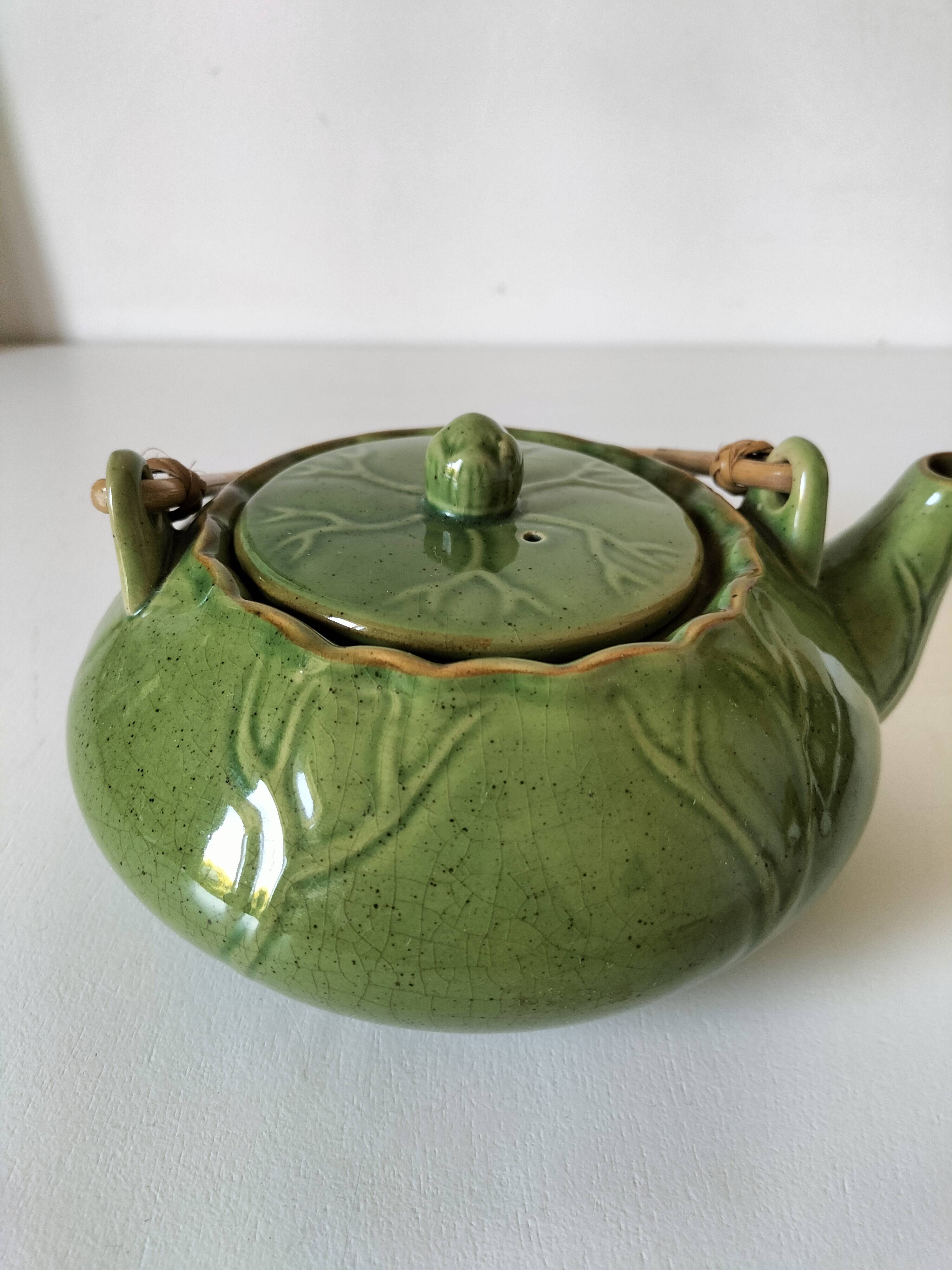 Vintage green teapot with lotus decoration and bamboo handle.