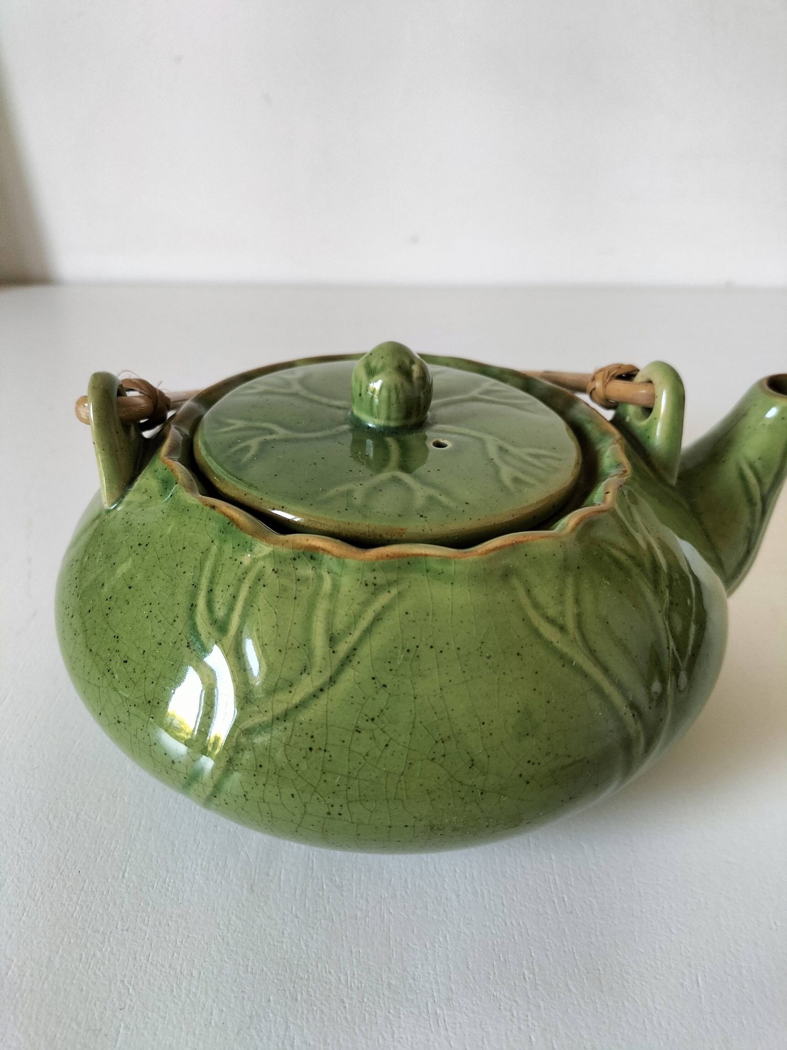 Vintage green teapot with lotus decoration and bamboo handle.