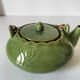 Vintage green teapot with lotus decoration and bamboo handle.