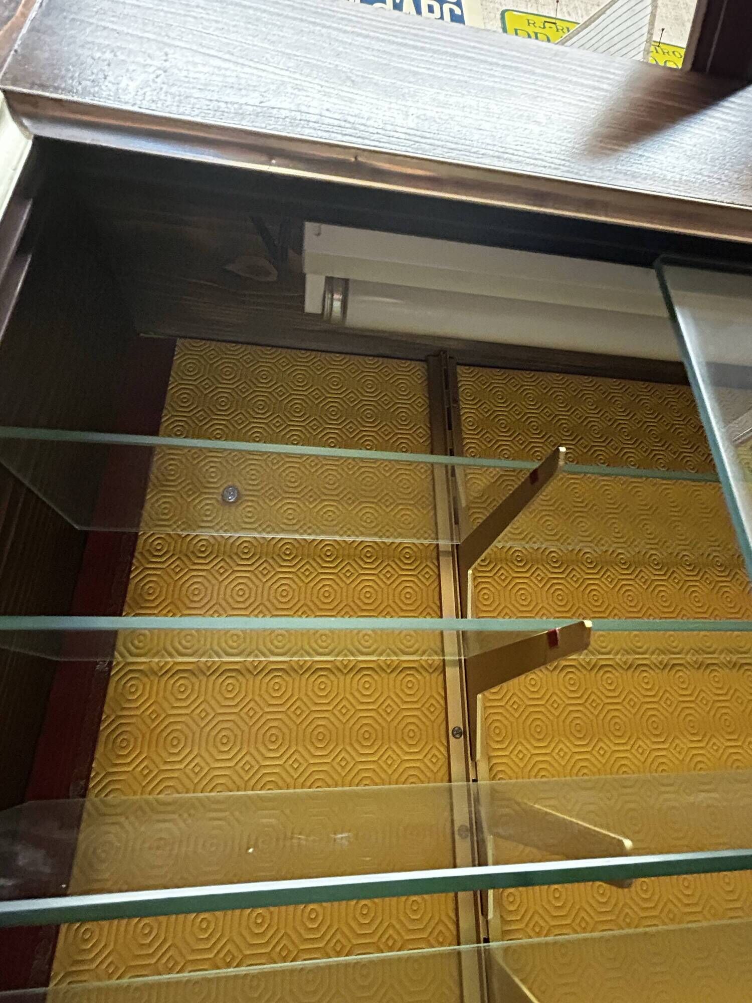 Vintage wooden and glass display cabinet, 15 shelves, gold background.